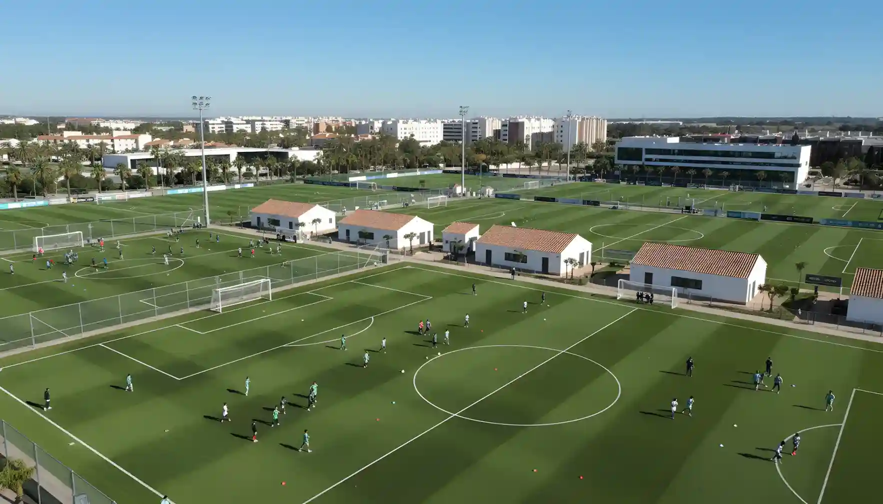 Instalaciones de entrenamiento de fútbol base con varios campos y jóvenes deportistas